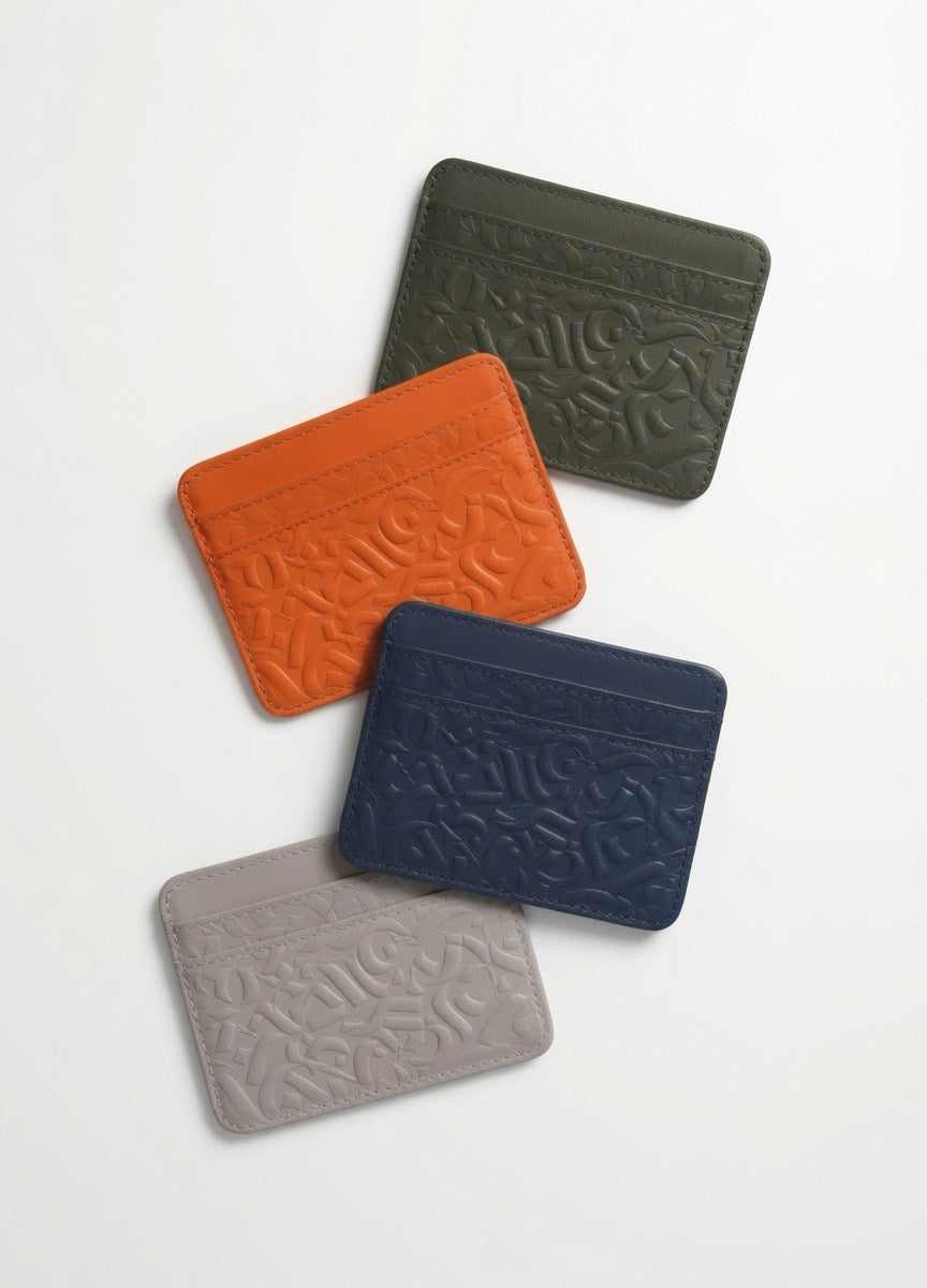 Four KADE and Co card holders in olive green, orange, navy blue and light grey with embossed pattern